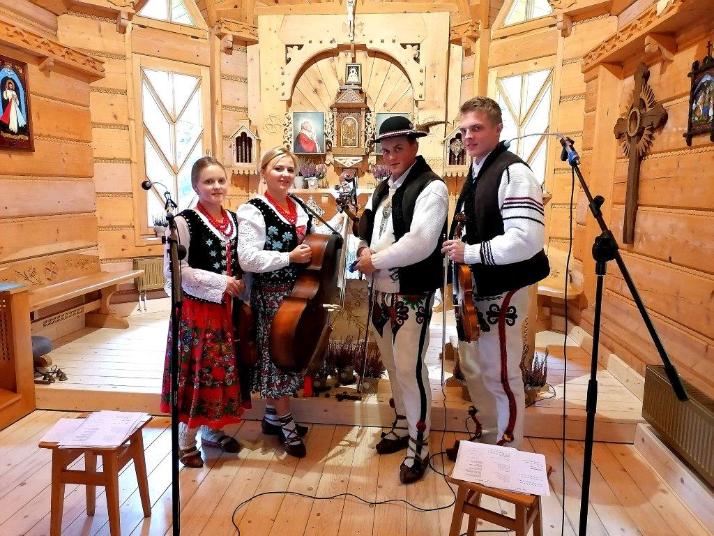 Zdjęcie zespołu Regionalnego Kasinianie - Zagórzanie w drewnianym kościółku. Dwie Panie i dwóch panów w regionalnych strojach.
