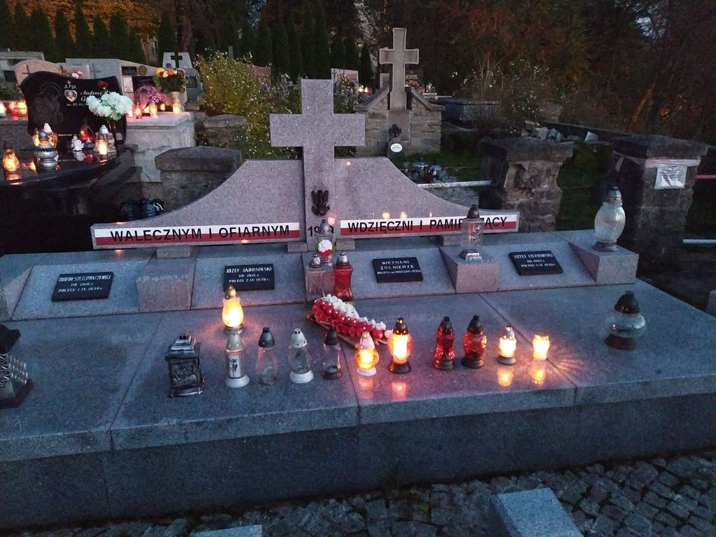 Widok na pomnik zołnierzy z zapaloymi zniczami.