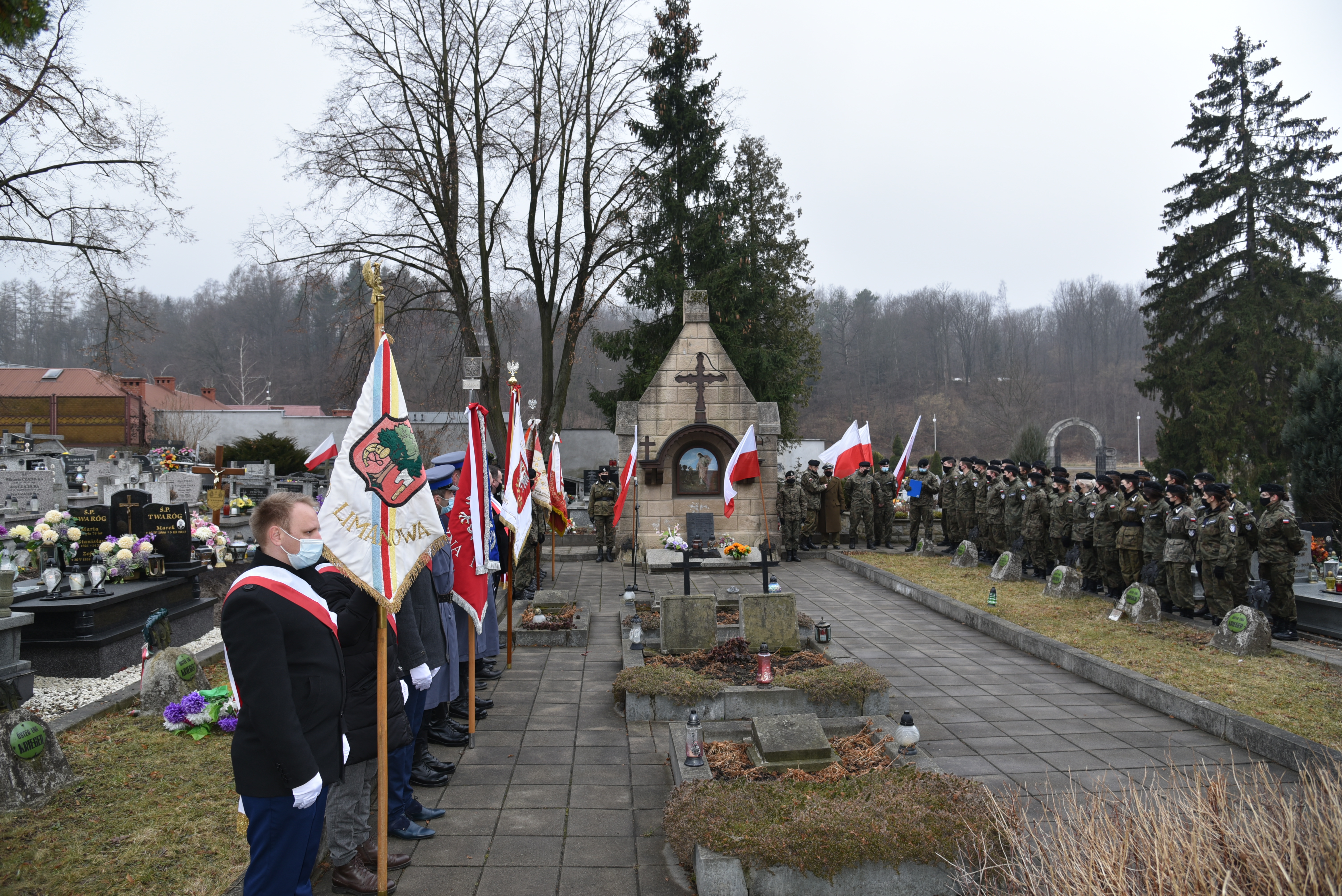 Widok na groby żołnierzy wyklętych na limanowskim cmentarzu. Po prawej stoi oddział jednostki strzelec, po lewej poczty sztandarowe.
