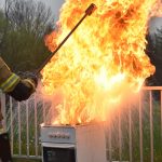 Przedstawiciel Państwowej Straży Pożarnej -Pokaz gaszenia kuchenki na Dniu Otwartym z Powiatową Radą Bezpieczeństwa Ruchu Drogowego