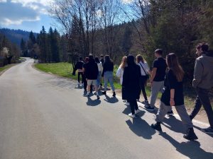 grupa młodzieży idzie w kolumnie asfaltową drogą