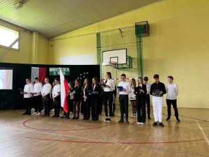 uczniowie z flagą Polski ustawieni w dwuszeregu