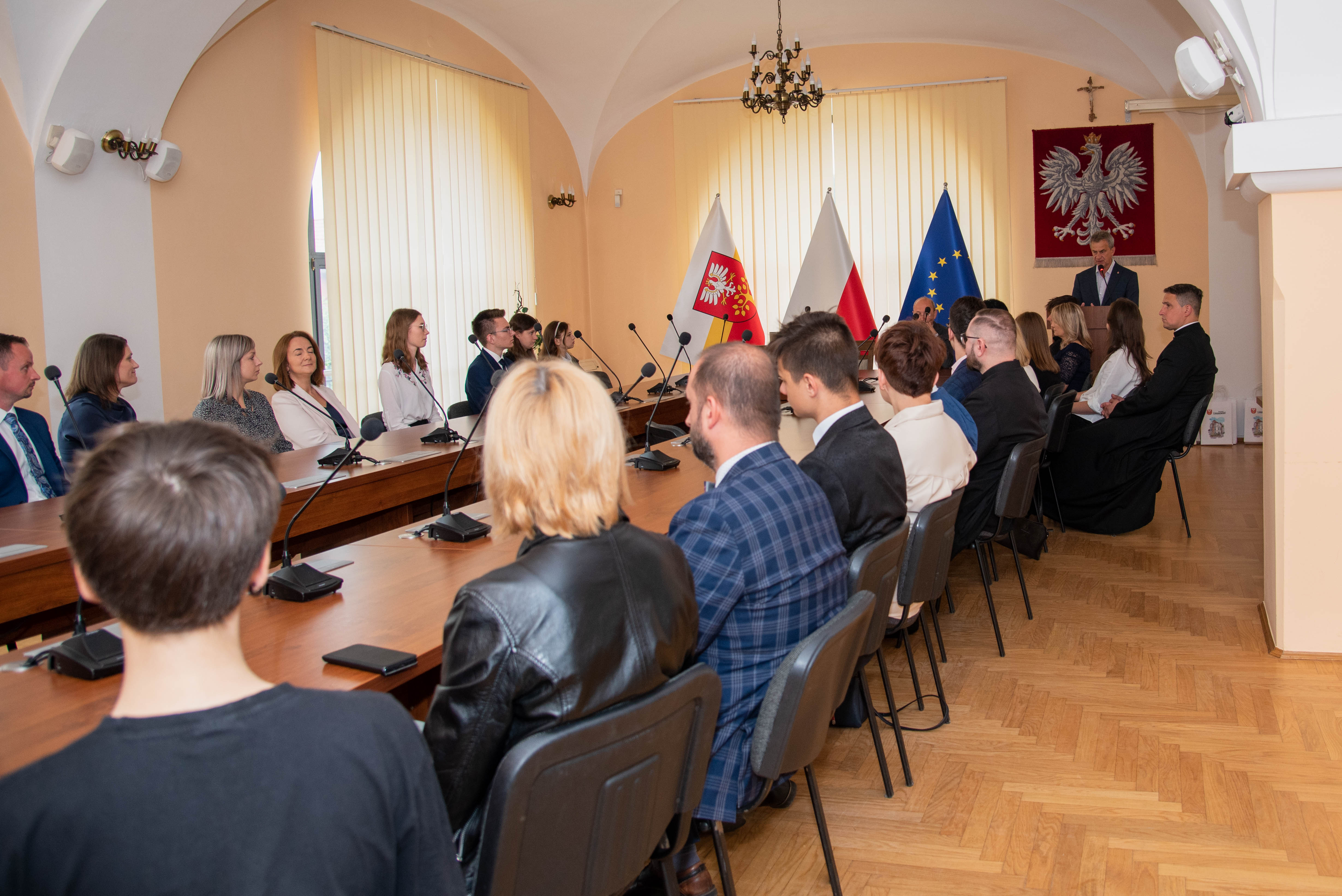 Dyrektorzy i nauczyciele szkół przy stole obrad na ambonie Mieczysław Uryga