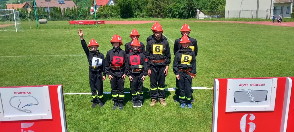 7 chłopców - strażaków stoi w dwurzędzie