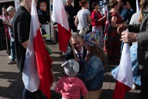 starosta rozmawia z małymi dziewczynkami, które trzymają flagi